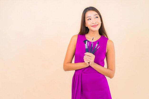 Portrait beautiful young asian woman with make up brush on color isolated background