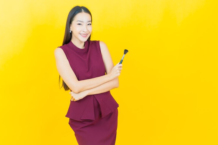 無料Photo 黄色の壁に化粧ブラシ化粧品と肖像画美しい若いアジアの女性