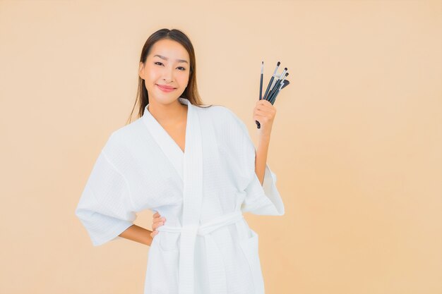 Portrait beautiful young asian woman with makeup brush on beige