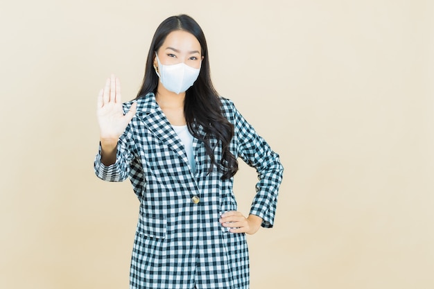Ritratto bella giovane donna asiatica con maschera per proteggere covid19 o virus su giallo