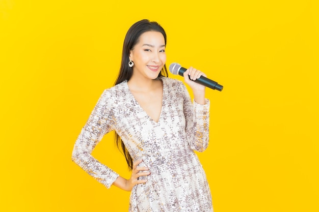 노란색에 노래에 대 한 마이크와 초상화 아름 다운 젊은 아시아 여자