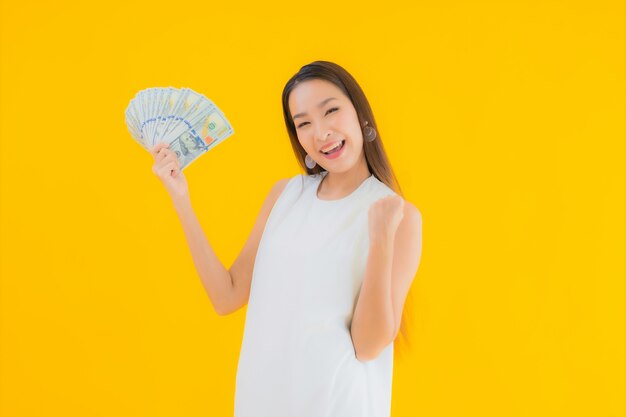 お金の現金を持つ美しい若いアジア女性の肖像画