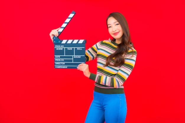 Женщина портрета красивая молодая азиатская с резкой шифера фильма на красной изолированной стене