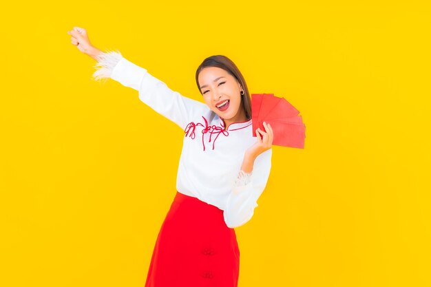 Portrait beautiful young asian woman with red envelopes letter in chinese new year on yellow