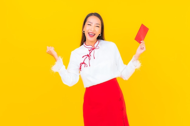 Free photo portrait beautiful young asian woman with red envelopes letter in chinese new year on yellow