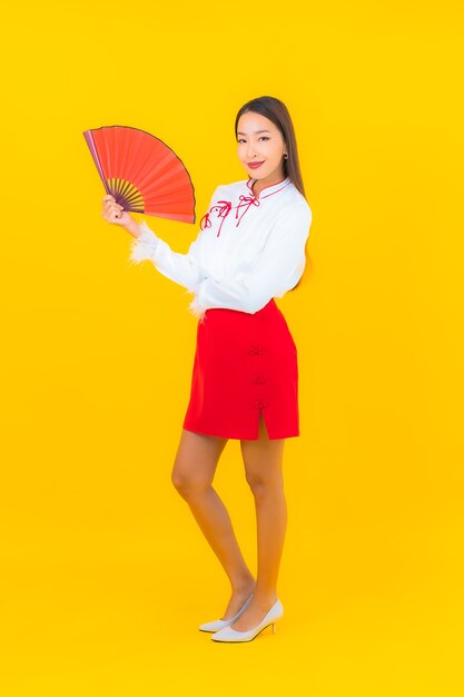 Портрет красивой молодой азиатской женщины с красным конвертом на желтом