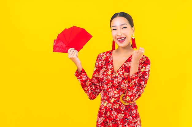 Portrait beautiful young asian woman with red envelopes on yellow wall