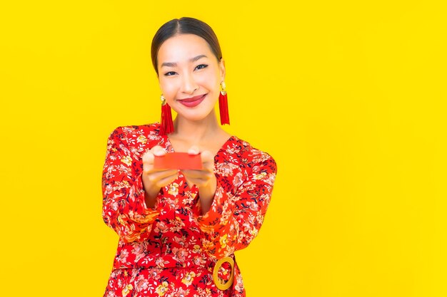 Portrait beautiful young asian woman with red envelopes on yellow wall