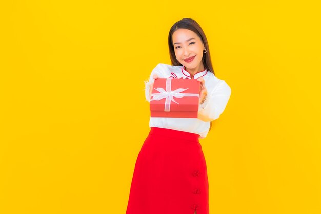 黄色に赤いギフト ボックスを持つ美しい若いアジアの女性の肖像画