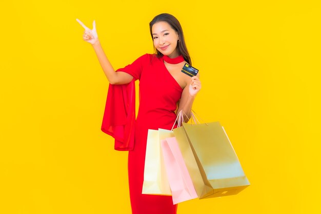 ショッピングバッグとクレジットカードを持つ肖像画の美しい若いアジアの女性