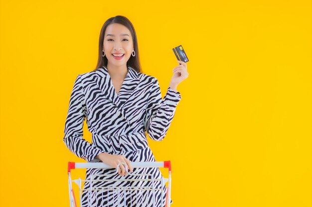 肖像画黄色の食料品の買い物のためのショッピングカートと美しい若いアジア女性