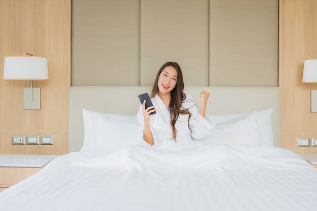 침실에서 스마트 휴대 전화와 초상화 아름 다운 젊은 아시아 여자