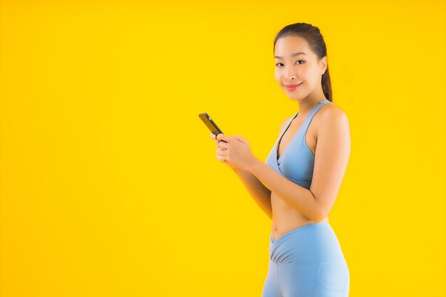 肖像画分離された黄色のスマート携帯電話を持つ美しい若いアジア女性
