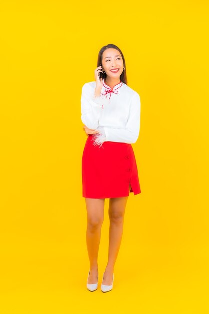 黄色のスマート携帯電話を持つ美しい若いアジア女性の肖像画