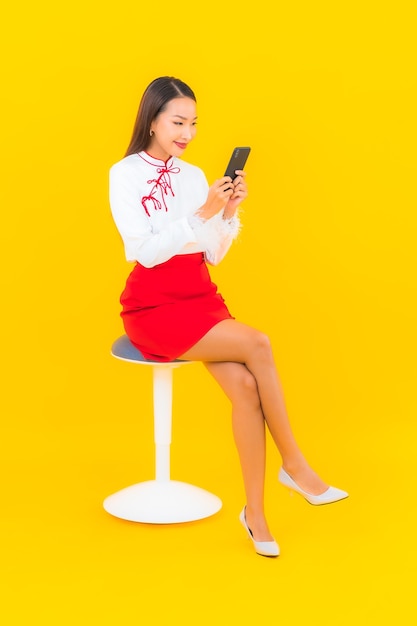 Portrait beautiful young asian woman with smart mobile phone on yellow