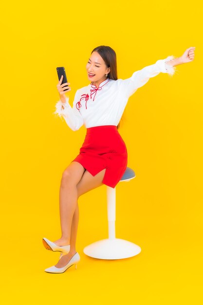 노란색에 스마트 휴대 전화와 초상화 아름 다운 젊은 아시아 여자