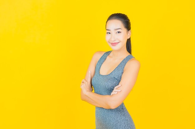黄色の壁に運動の準備ができてスポーツウェアと肖像画の美しい若いアジアの女性