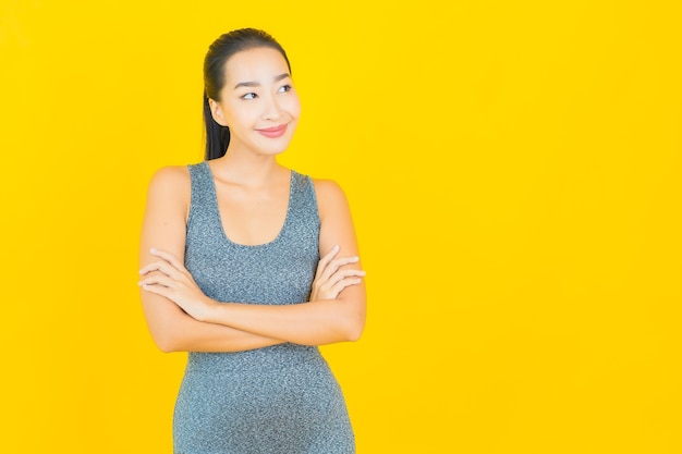 Portrait beautiful young asian woman with sportswear ready for exercise on yellow wall