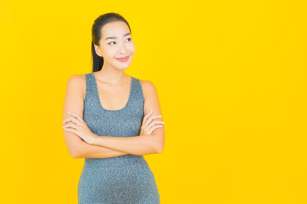 노란색 벽에 운동을위한 준비 운동복 초상화 아름 다운 젊은 아시아 여자