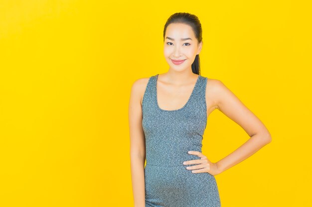 노란색 벽에 운동을위한 준비 운동복 초상화 아름 다운 젊은 아시아 여자