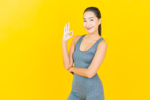 Portrait beautiful young asian woman with sportswear ready for exercise on yellow wall