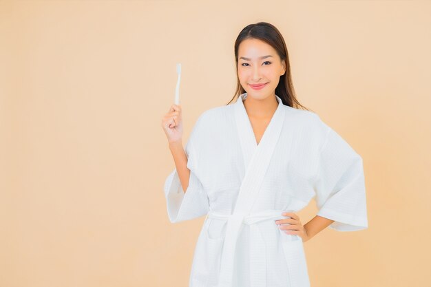 Portrait beautiful young asian woman with toothbrush on beige
