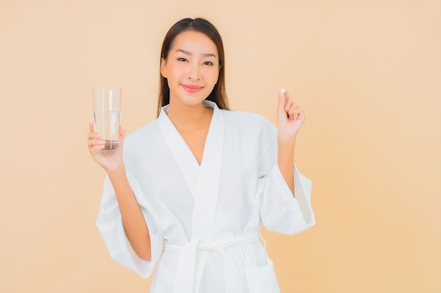 Portrait beautiful young asian woman with water glass and drug pill on beige