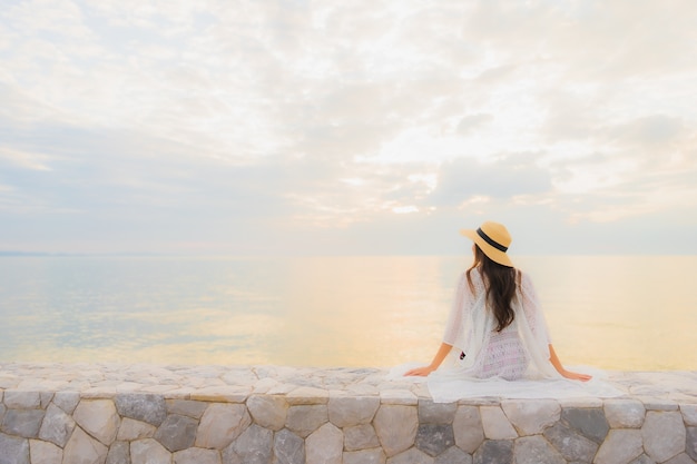 Il sorriso felice delle belle giovani donne asiatiche del ritratto si rilassa intorno all'oceano della spiaggia del mare