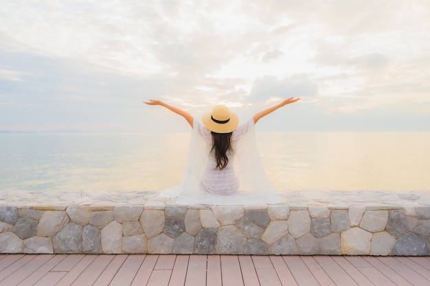 Foto gratuita il sorriso felice delle belle giovani donne asiatiche del ritratto si rilassa intorno all'oceano della spiaggia del mare