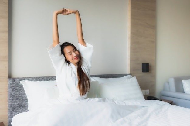 Il sorriso felice delle belle giovani donne asiatiche del ritratto si rilassa sul letto