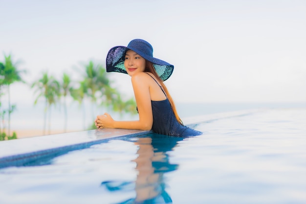 Улыбка красивых молодых азиатских женщин портрета счастливая ослабляет открытый бассейн в гостинице