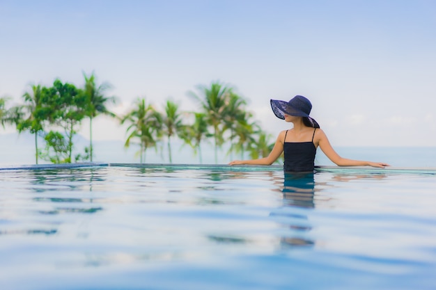 Foto gratuita il sorriso felice delle belle giovani donne asiatiche del ritratto si rilassa la piscina all'aperto in hotel