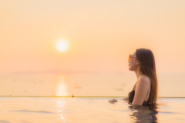 Foto gratuita il sorriso felice delle belle giovani donne asiatiche del ritratto si rilassa la piscina all'aperto in hotel