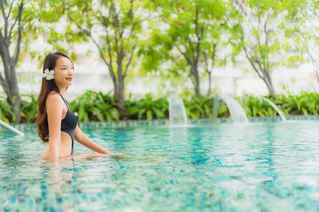 Улыбка красивых молодых азиатских женщин портрета счастливая ослабляет открытый бассейн в курорте