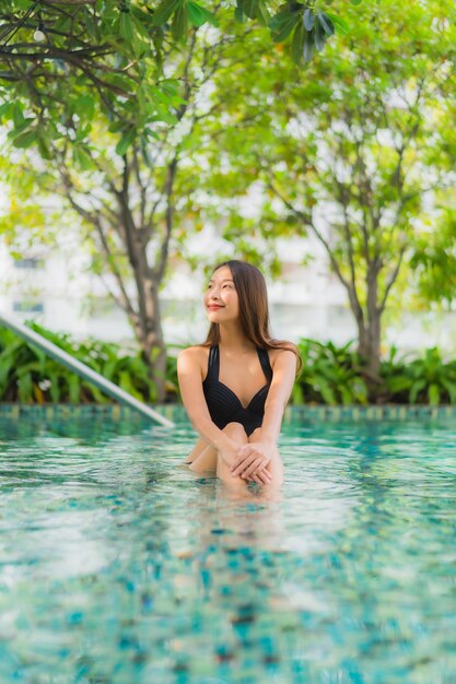 肖像画美しい若いアジア女性の幸せな笑顔はリゾートの屋外スイミングプールをリラックスします。