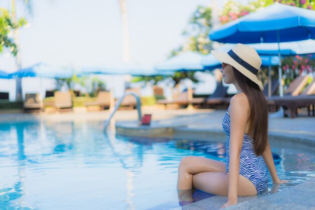 Улыбка красивых молодых азиатских женщин портрета счастливая ослабляет открытый бассейн в курорте