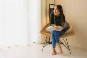 無料写真 肖像画美しい若いアジア女性の幸せな笑顔はソファの椅子に座ってリラックスします。