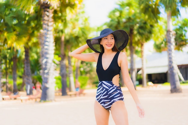 Le belle giovani donne asiatiche del ritratto si rilassano il sorriso felice intorno all'oceano della spiaggia del mare