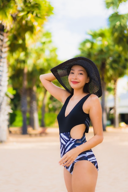 Женщины портрета красивые молодые азиатские ослабляют улыбку счастливую вокруг моря пляжа океана