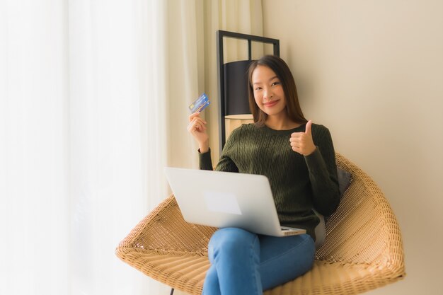 온라인 쇼핑을 위해 신용 카드로 컴퓨터 노트북을 사용하는 세로 아름다운 젊은 아시아 여성