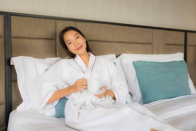 침대에 커피 컵 초상화 아름 다운 젊은 아시아 여성