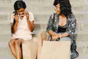 Free photo portrait of beautiful young black women with shopping bags