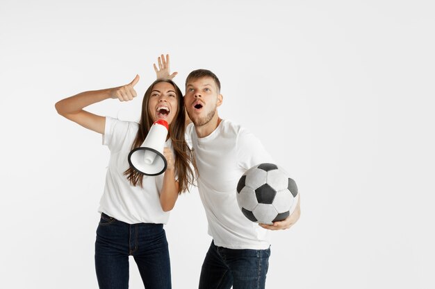 Portrait of beautiful young couple football or soccer fans on white  space. Facial expression, human emotions, advertising, sport concept
