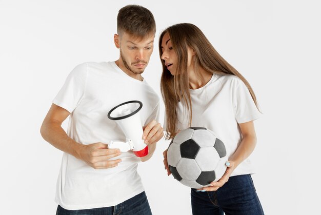 Portrait of beautiful young couple football or soccer fans on white  space. Facial expression, human emotions, advertising, sport concept