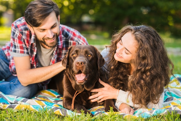 Portrait of a beautiful young couple with their dog in garden