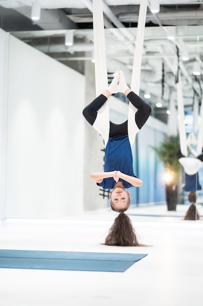 Free photo portrait of a beautiful young girl engaged in fly yoga on canvases.