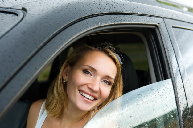 Portrait of beautiful young happy woman in the new car  - outdoors