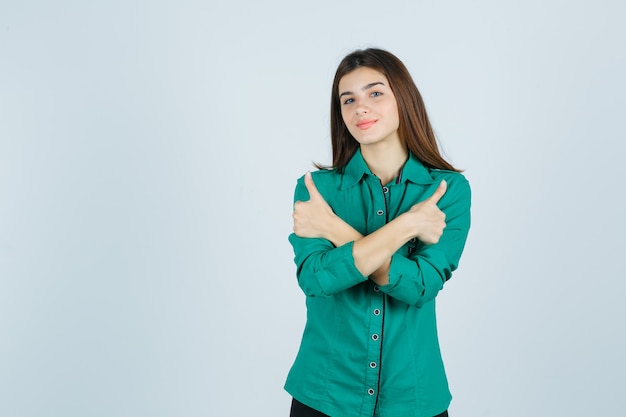 Portrait of beautiful young lady showing double thumbs up in green shirt and looking cheery front view