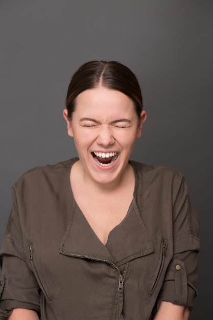 Foto gratuita ritratto di bella giovane signora sorridente in studio dalla felicità. bella signora grande che ride con gli occhi chiusi