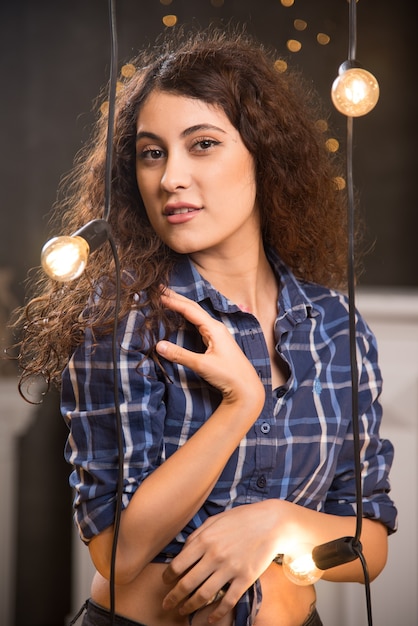 Portrait of a beautiful young model in plaid shirt posing near lamps